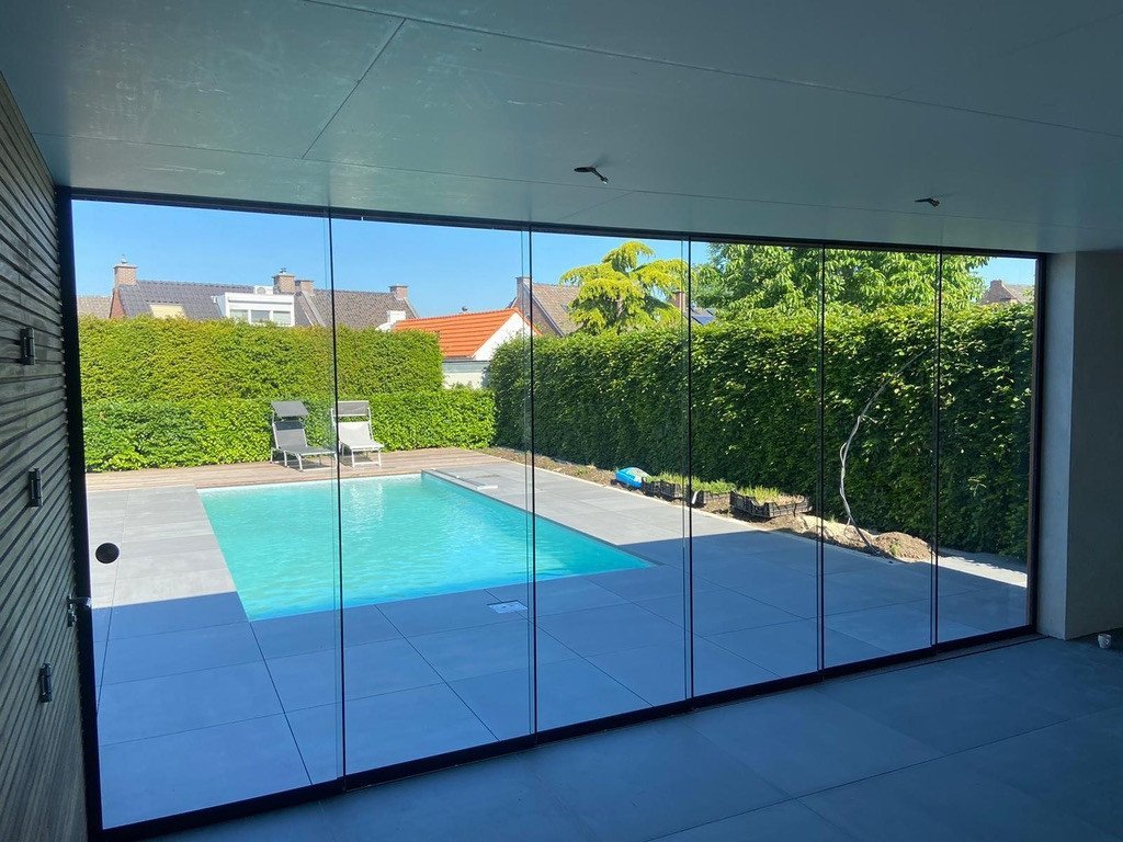 Luxe glazen schuifwand voor een stijlvolle tuin in Sittard-Geleen of elders in Limburg. Glazen schuifwand met uitzicht op een modern zwembad en strak omheinde tuin in Sittard-Geleen Limburg.