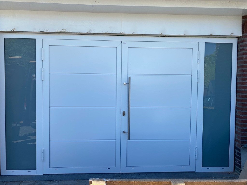 Witte openslaande witte garagedeuren in Sittard-Geleen én Limburg. Openslaande witte garagedeuren met glazen panelen in Sittard-Geleen én Limburg.