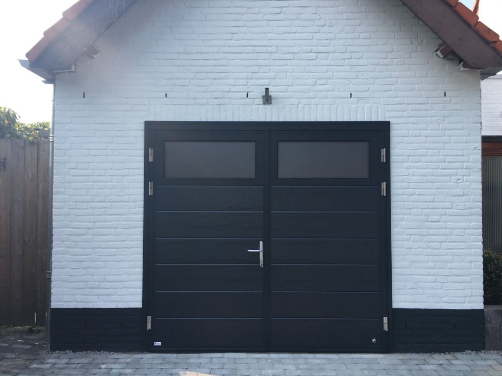 Stijlvolle zwarte openslaande garagepoort voor uw garage. Zwarte openslaande garagepoort met glazen panelen en moderne uitstraling, geplaatst op een woning.